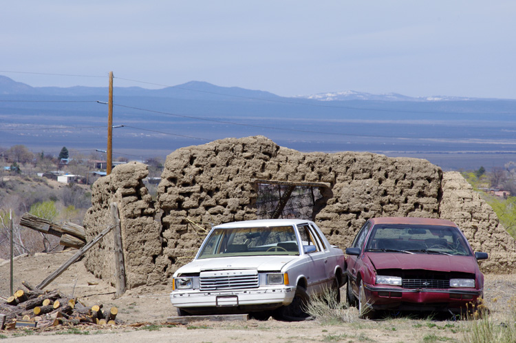 A crumbling adobe with dead cars in Taos, NM