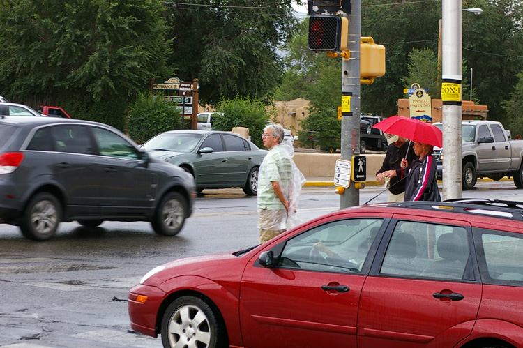 tourist in the rain crossing a street in Taos